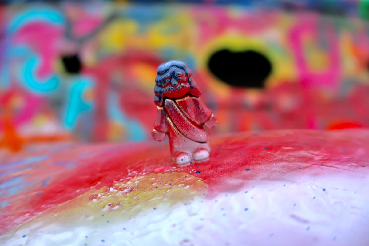 A small figurine stands on a colorful, abstract background.
