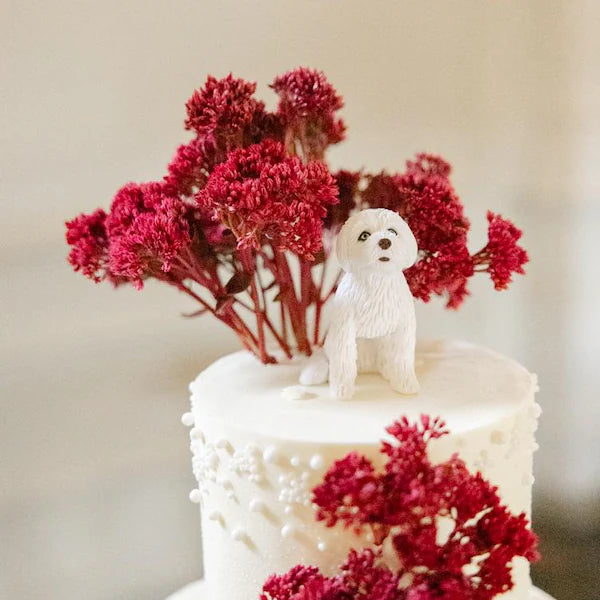 Dog figurine on a wedding cake with red flowers, from Harrison’s published customer review
